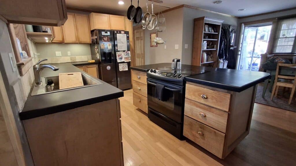 A modern kitchen featuring a black countertop and warm wooden cabinets, creating a stylish and inviting atmosphere.