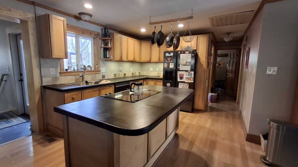 A modern kitchen featuring a black countertop and warm wooden cabinets, creating a stylish and inviting atmosphere.