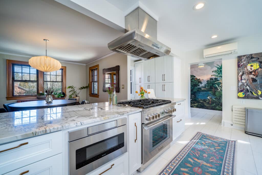 Modern kitchen with white cabinets, stainless steel appliances, marble countertops on the counter.