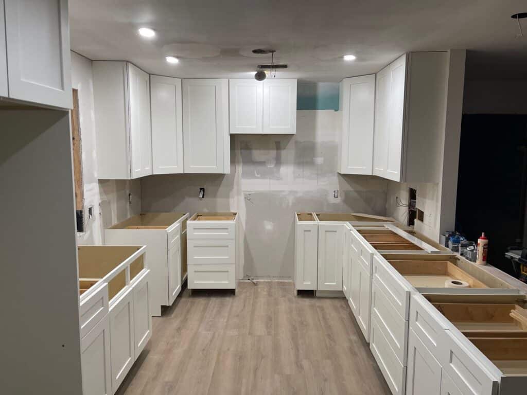 Modern kitchen featuring white cabinets and warm wood floors, showcasing a stylish remodeling design.