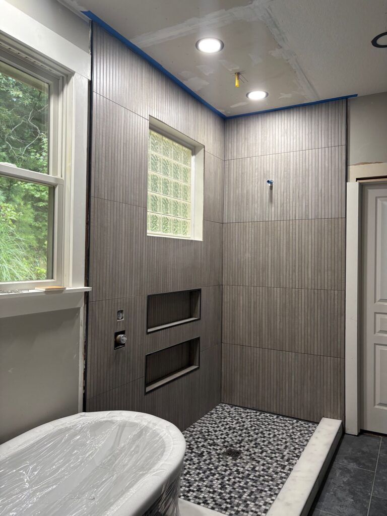 A bathroom remodeling proccess featuring a sleek shower and a stylish tub, showcasing contemporary design elements and finishes.